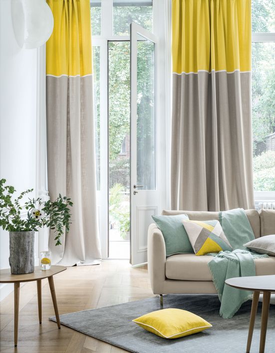 Cortinas y cojines de color amarillo y gris a juego con el color del sofá